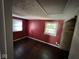 Red bedroom with hardwood floors, two windows for natural light, and a closet at 3403 Coffey St, Indianapolis, IN 46217