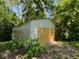 Exterior of the shed with a boarded up door surrounded by overgrown foliage at 3403 Coffey St, Indianapolis, IN 46217
