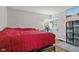 Comfortable bedroom with a red bedspread, hardwood floors, and a large window at 376 S Arlington Ave, Indianapolis, IN 46219