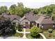 Aerial view of townhome complex with mature trees, landscaped grounds, and well-maintained roofs at 3852 Knollton Rd # 3852, Indianapolis, IN 46228