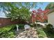 Beautifully landscaped front yard with brick accent wall, mature trees and plants, and a charming bench at 410 Sugar Tree Ln, Indianapolis, IN 46260