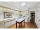 Well-lit kitchen featuring white cabinets, skylight, island table and hardwood floors at 410 Sugar Tree Ln, Indianapolis, IN 46260
