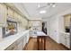 Well-lit kitchen featuring white cabinets, skylight, island table and hardwood floors at 410 Sugar Tree Ln, Indianapolis, IN 46260