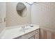 Elegant powder room featuring patterned wallpaper, a stylish round mirror, and a white vanity at 410 Sugar Tree Ln, Indianapolis, IN 46260