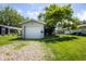 Garage with a white door, gravel driveway, green lawn, and large tree providing shade at 4625 N Sadlier Dr, Indianapolis, IN 46226