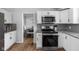 Modern kitchen with white cabinets, stainless steel appliances, and hardwood floors, leading to the dining area at 469 Ash Dr, Carmel, IN 46032