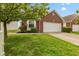 Brick home featuring an attached two-car garage, tidy landscaping, and concrete driveway under a clear blue sky at 5503 Wilder Way, Indianapolis, IN 46216