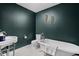 Charming bathroom features a clawfoot tub, pedestal sink, and stylish dark green walls at 609 E 39Th St, Indianapolis, IN 46205