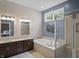 Bright bathroom featuring a double vanity, soaking tub, glass shower, and elegant decorative accents at 654 N Senate Ave, Indianapolis, IN 46202