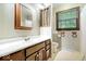 A charming bathroom with a classic wood vanity, stylish wallpaper, and a bright, airy window at 659 Carson Ct, Carmel, IN 46033