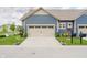 Attractive townhome showcases blue siding, a two-car garage, and a beautifully landscaped front yard at 7077 Antiquity Dr, Carmel, IN 46033