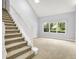 Carpeted staircase in a room featuring a vaulted ceiling, large window, and natural light at 7513 Pine Royal Dr, Indianapolis, IN 46256