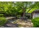 Shady backyard patio with a table and chairs, offering a serene outdoor space surrounded by lush greenery at 7575 Central Ave, Indianapolis, IN 46240