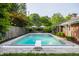 An in-ground pool surrounded by a stone patio, lush landscaping, and an inviting poolside area at 7575 Central Ave, Indianapolis, IN 46240