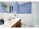 Stylish bathroom featuring a modern vanity, round mirror, and blue accent wall at 7734 Hoover Rd, Indianapolis, IN 46260
