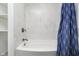 Clean bathroom with tub, shower, and elegant white marble-look tile at 7734 Hoover Rd, Indianapolis, IN 46260