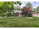 Charming single-story brick home with a well-manicured lawn and mature trees, offering great curb appeal at 7734 Hoover Rd, Indianapolis, IN 46260