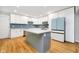 Modern kitchen featuring white cabinets, stainless steel appliances, a center island, and blue backsplash at 7734 Hoover Rd, Indianapolis, IN 46260
