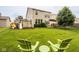 A charming backyard featuring a swing set, deck, lush greenery, and comfortable seating area with green Adirondack chairs at 7824 Hedgehop Dr, Zionsville, IN 46077