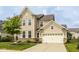 Classic two-story home boasting a two-car garage, beige siding, stone veneer, and a well-maintained lawn at 7824 Hedgehop Dr, Zionsville, IN 46077