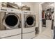 Modern laundry room showcases front loading washer and dryer, with a glimpse into the closet at 7824 Hedgehop Dr, Zionsville, IN 46077