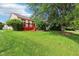 A well-manicured lawn and trees lead up to a red stained deck on the rear of the home at 7970 Cobblesprings Dr, Avon, IN 46123
