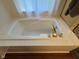 Close-up of a white bath tub with gold fixtures and white tiled walls at 7970 Cobblesprings Dr, Avon, IN 46123