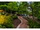 Lush backyard retreat with serene garden pathway, brick edging, and Adirondack chairs, inviting relaxation in nature at 8209 Beech Knoll, Indianapolis, IN 46256