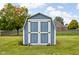 A sturdy backyard shed with painted blue wood panels offers ample storage space and convenience on manicured lawn at 9159 E County Road 400 N, Brownsburg, IN 46112