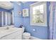 Light blue bathroom features a single sink vanity, toilet, storage cabinet, and a window at 10390 Tremont Dr, Fishers, IN 46037