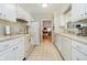 Galley kitchen with white cabinets, appliances, and tile flooring with a view of an adjacent living space at 1045 Millwood Ct, Indianapolis, IN 46260