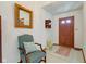 Welcoming foyer with tiled floor, featuring a charming chair, decorative mirror, and wooden door at 12258 Charing Cross Rd, Carmel, IN 46033