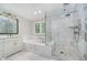 Beautiful bathroom features a marble tile shower, a soaking tub under a window, and vanity with a white counter at 12563 Sandstone Run, Carmel, IN 46033
