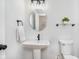 Cozy powder room showcasing a pedestal sink, round mirror, and stylish fixtures at 12563 Sandstone Run, Carmel, IN 46033