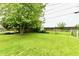 Expansive backyard featuring lush green grass, a mature tree, and a wooden fence at 1440 Brandt Dr, Indianapolis, IN 46241