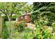 View of a cozy home with a ramp, surrounded by a colorful garden and mature trees at 1440 Brandt Dr, Indianapolis, IN 46241