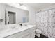 Bathroom featuring dual sinks, white cabinets, and a patterned shower curtain at 15580 Garrano Ln, Fishers, IN 46040