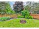 Firepit surrounded by a lush green backyard, plants, and wooden fence at 1649 Woodstock Dr, Brownsburg, IN 46112