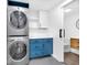 Convenient laundry area with stackable washer and dryer, marble countertop, and blue cabinets, next to a bathroom at 19 E Regent St, Indianapolis, IN 46225