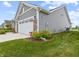 View of home's gray siding and stone veneer with manicured shrubs, green lawn and attached two car garage at 19657 Astoria Ave, Sheridan, IN 46069