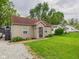 Exterior view of cozy single-story home with mature trees, an expansive lawn, and gravel driveway at 2353 E 10Th St, Anderson, IN 46012