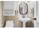 Cozy bathroom with pedestal sink, decorative mirror, storage shelving, and toilet at 305 N 1100 E, Zionsville, IN 46077
