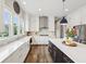 Bright kitchen with stainless steel appliances, white cabinets, large island, and hardwood floors at 3316 Shelborne Woods Pkwy, Carmel, IN 46032