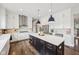 Modern kitchen with white cabinets, dark island and stainless steel appliances featuring pendant lighting at 3316 Shelborne Woods Pkwy, Carmel, IN 46032