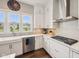 Updated kitchen featuring stainless steel appliances, white cabinetry, farmhouse sink, and hardwood floors at 3316 Shelborne Woods Pkwy, Carmel, IN 46032