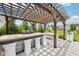 Outdoor kitchen under a wooden pergola featuring a built-in grill and bar seating at 3316 Shelborne Woods Pkwy, Carmel, IN 46032