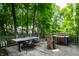 Outdoor deck with dining table and grill, surrounded by lush trees at 410 Somerset W Dr, Indianapolis, IN 46260