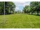 Lush green space surrounded by mature trees and blue skies at 4232 Linden Ln, Anderson, IN 46011