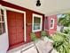 Inviting front porch with red siding, green chairs and an open doorway at 4714 Crestview Ave, Indianapolis, IN 46205