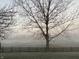 A tranquil backyard view with a wooden fence overlooking a serene golf course in foggy conditions at 4818 Arabian Run, Indianapolis, IN 46228